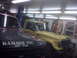 1994 Ford F-250 - A yellow pickup truck is parked next to a dark-colored truck in an indoor setting.