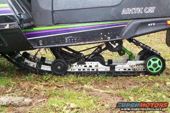 Snowmobile side view showing track, suspension, and "ARCTIC CAT" text