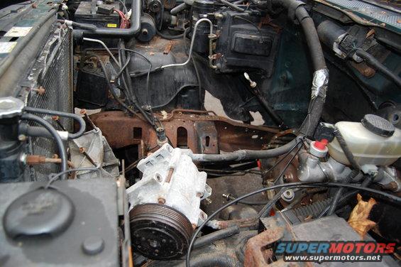 Engine bay with parts removed, showing the radiator, compressor, and brake fluid reservoir