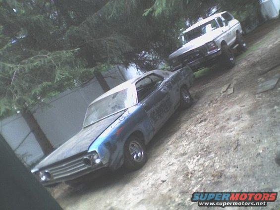 1969 Ford Torino in primer next to a white Ford Bronco