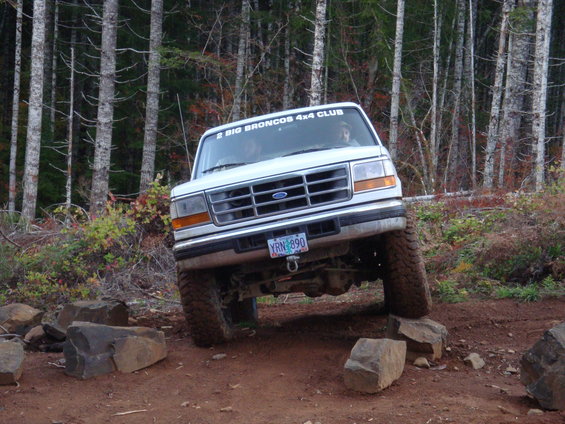 White Ford Bronco with '2 BIG BRONCOS 4X4 CLUB' sticker on windshield, navigating rocky terrain
