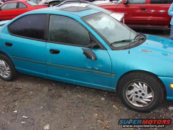 Teal sedan with a sunroof and tinted windows parked on dirt. Another red vehicle is behind it