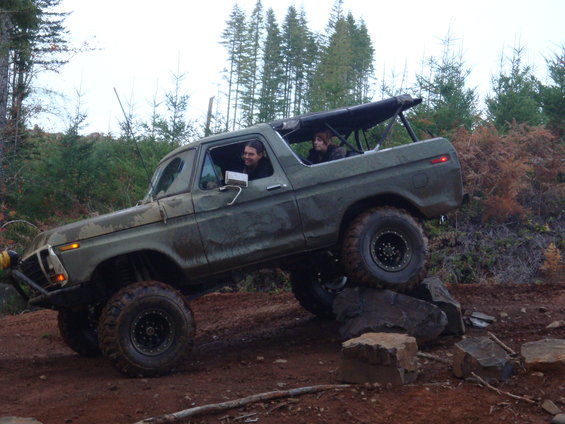 Olive green 1978 Ford Bronco climbing rocks on a trail