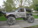 1984 Ford Bronco II - This heavily modified Ford pickup truck, likely from the early 1980s, is equipped for off-road use with large tires and a custom roll cage.