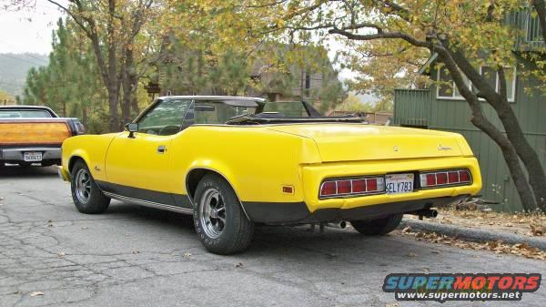 Yellow 1973 Mercury Cougar convertible parked on street, another vehicle visible to the left