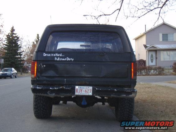 Rear view of a black 1985 Ford Bronco with a sticker that says "Drive it in Hard... Pull it out Dirty"
