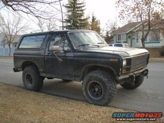Black Ford Bronco with aftermarket wheels and tires parked on a dirt shoulder