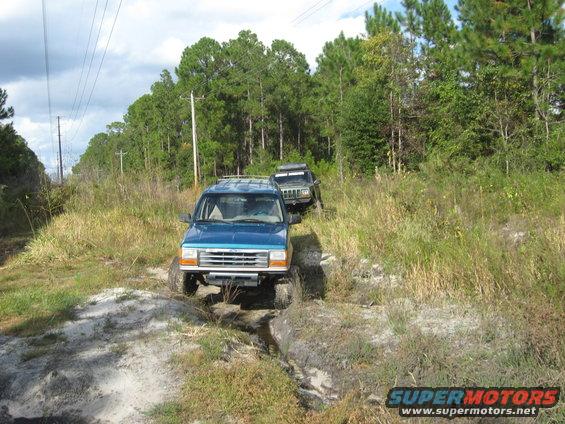 Blue 1992 Ford Explorer driving on a dirt path with another SUV behind it