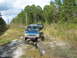 1992 Ford Explorer - Two SUVs navigate a rough dirt trail surrounded by trees and tall grass.
