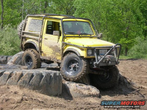Yellow off-road vehicle with roll cage navigating mud obstacle