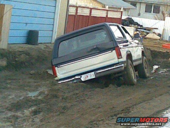 Ford Bronco stuck in dirt and mud, rear view. License plate is visible