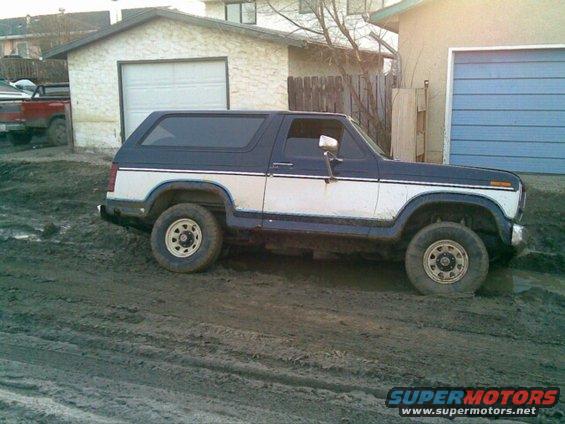 Blue and white Ford Bronco parked in mud