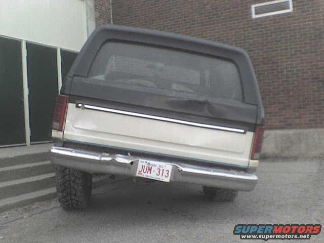 Rear view of a 1985 Ford Bronco parked near a brick building