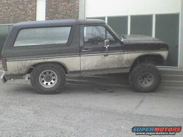 Two-tone black and tan Ford Bronco with a camper shell, seen from the side
