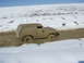 1985 Ford Bronco - This 1985 Ford Bronco is deeply stuck in a muddy terrain, with snow visible on the surrounding hills.