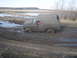 1985 Ford Bronco - This SUV is deeply stuck in thick mud, with water pooling around it.