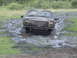 1985 Ford Bronco - This SUV is stuck in the mud, its front tires submerged in the muck.