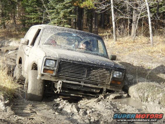 Mud-covered SUV navigating a rough, muddy terrain