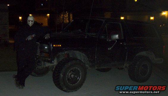 Black 1985 Ford Bronco with person in mask