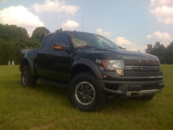 Black Ford F-150 SVT Raptor pickup truck parked on grass