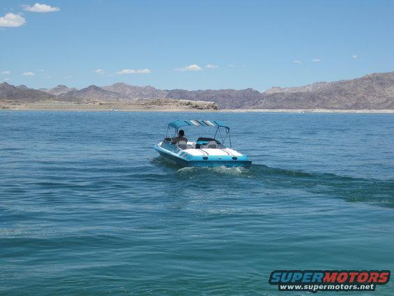 Blue and white boat with a striped canopy on a lake, seen from behind