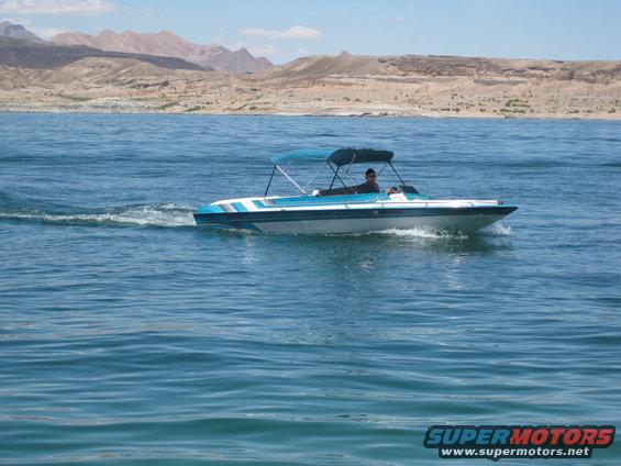 Boat with a blue canopy moving on a lake with mountains in the background