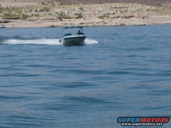 Boat with a canopy moving on the water, creating a wake