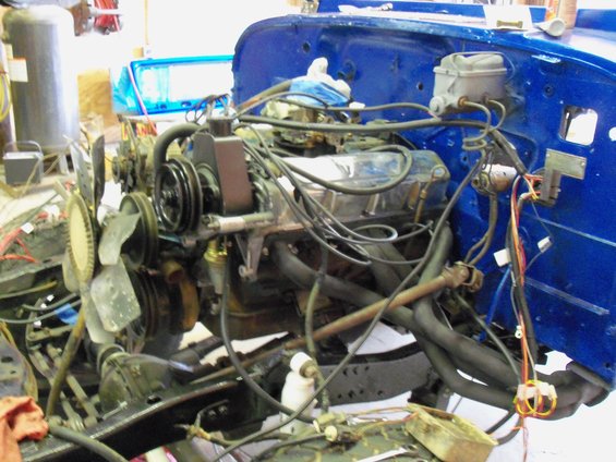 engine bay with blue firewall, chrome valve covers, and exhaust manifolds