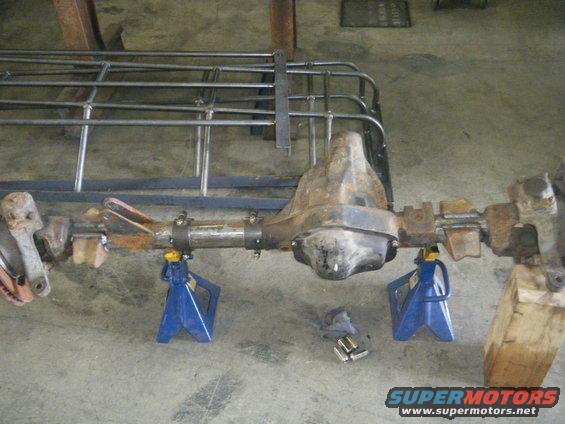 Rear axle assembly on jack stands with metal rack in background