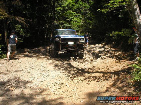Blue off-road SUV with large tires on a rocky trail