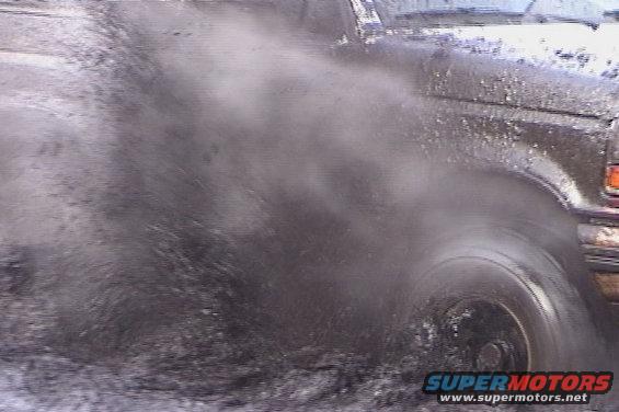 1993 Ford Bronco kicking up mud while driving