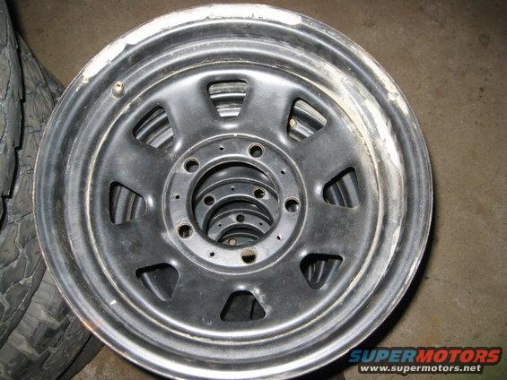 Stack of black steel wheels with visible lug nut holes and some chipped paint