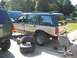 1992 Ford Explorer - A tan and teal 1992 Ford Explorer is parked outside with spare tires and tools nearby, suggesting maintenance work.