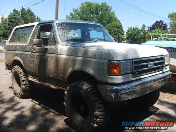 Mud-covered 1989 Ford Bronco with large off-road tires parked outdoors