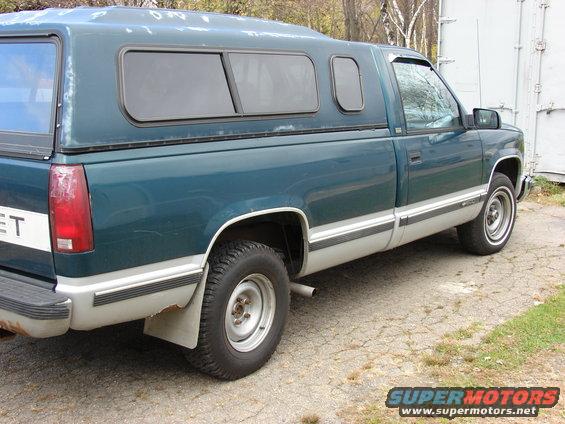 Teal pickup truck with camper shell, side view. Appears to be a 1990s Chevrolet