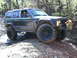 1994 Ford F-250 - A driver navigates a muddy off-road course in a lifted Jeep Cherokee XJ.