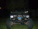 1984 Ford Bronco II - A modified 1984 Ford Bronco II is parked on grass at night, showing its front end with large tires and a winch.