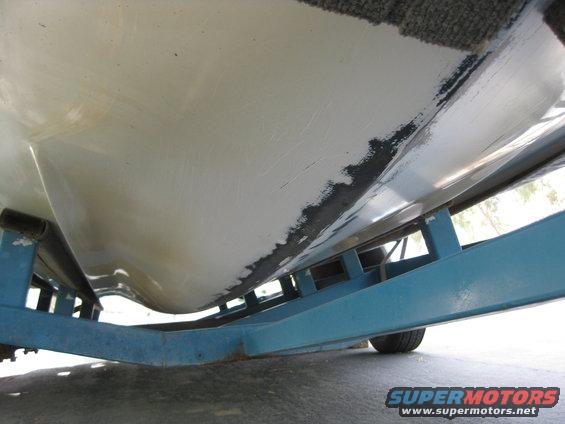 Underside of a boat hull resting on a blue trailer frame