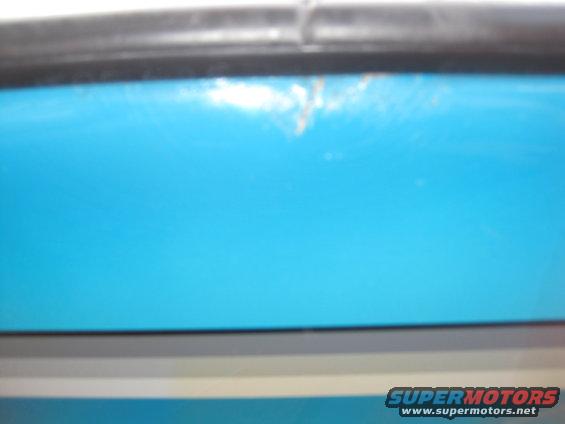 Close-up of a blue boat hull with a black trim piece above it. Supermotors.net logo visible