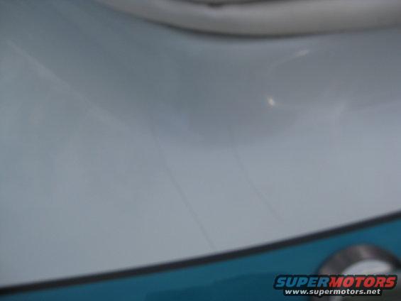 close-up of light blue boat hull with faint lines and a chrome fitting