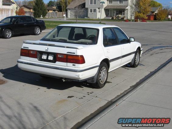 White 1989 Honda Accord sedan parked on concrete, rear 3/4 view, with a black sedan in the background