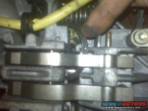 Close-up of a metal engine component with a yellow hose and a finger