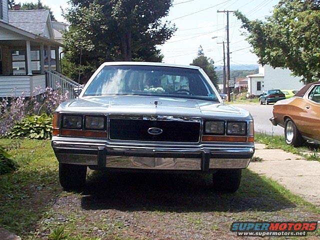 Silver 1991 Ford Crown Victoria front view. Another car is parked to the right
