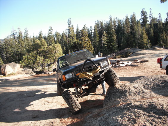 Black off-road SUV climbing a rock with a white SUV in the background