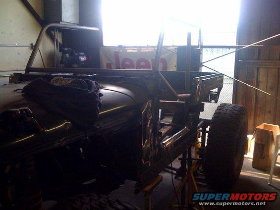 Side view of a 1994 Jeep YJ with custom roll cage and unfinished bodywork