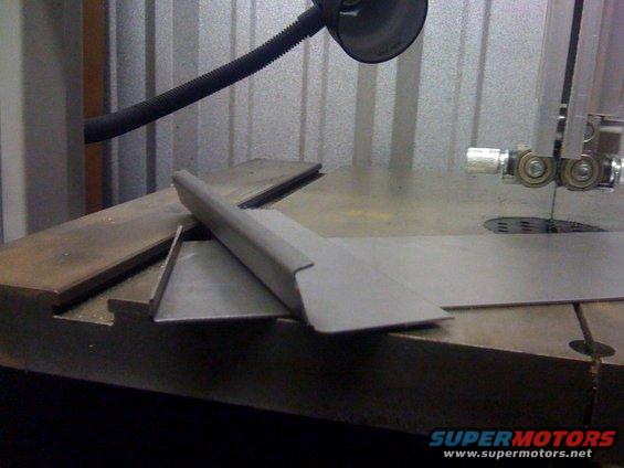 metal pieces on a band saw table, ready for cutting