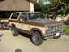 1986 Ford Bronco - This 1986 Ford Bronco features a two-tone brown and tan paint scheme and is parked in front of a garage.