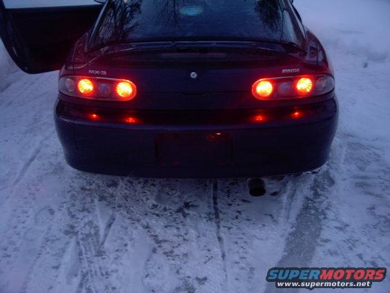 Dark Mazda MX-3 rear with taillights on in the snow