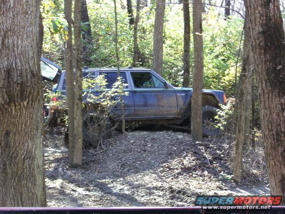 Jeep Cherokee XJ driving on a dirt trail in the woods