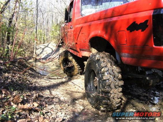 Red 1994 Ford F-250 off-roading in mud, 3/4 front view